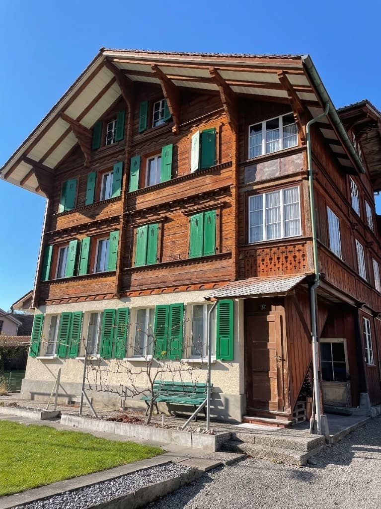 Traditionelles Schweizer Holzhaus an der Freihofstrasse 18 in Unterseen, mit Holzfassade, grünen Fensterläden und massivem Sockelgeschoss